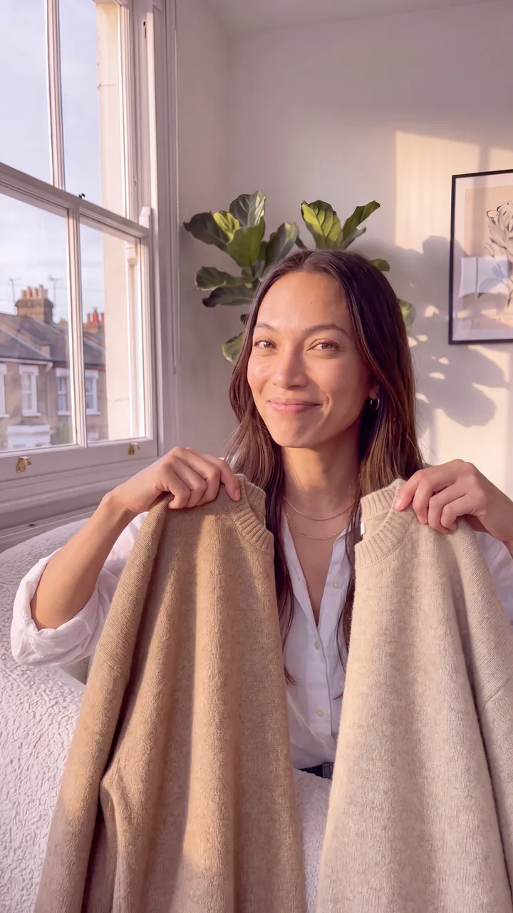 Mia Aquino holding two camel jumpers in her flat